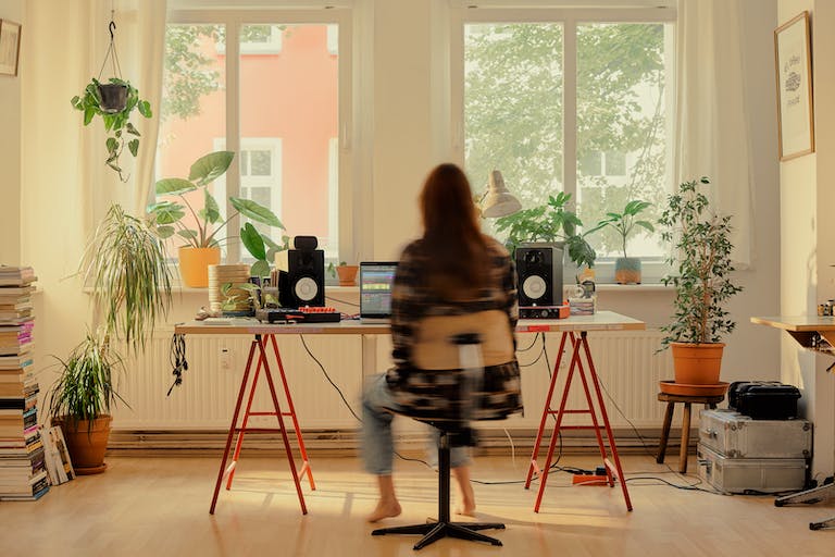 A music-maker sits at the desk in her studio, using Ableton Live to develop a musical idea she started in Note.